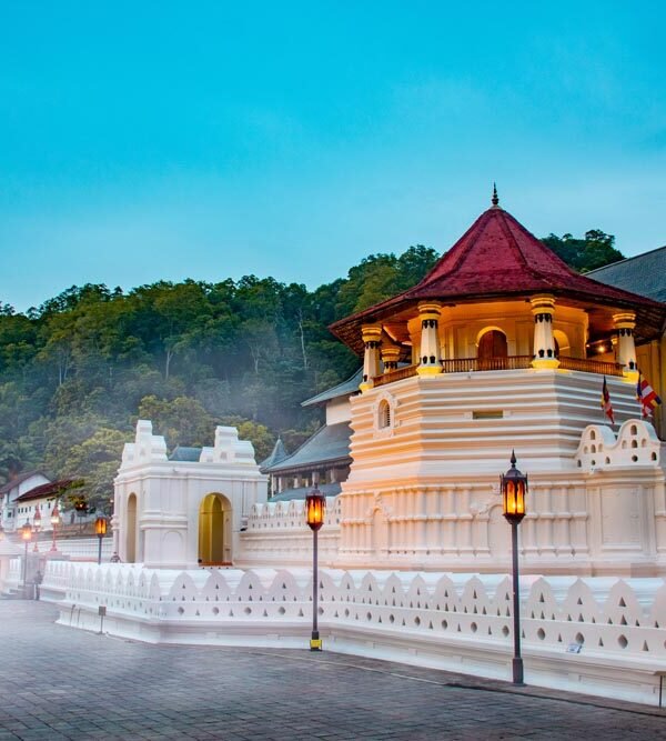 Aerial view of the picturesque city of Kandy surrounded by lush green hills, with the Temple of the Tooth Relic and Kandy Lake prominent in the center.